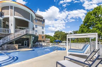 A large swimming pool is surrounded by a white fence and chairs.